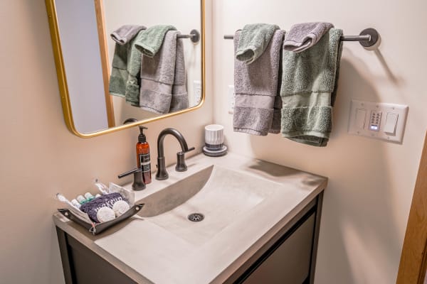 Modern bathroom sink area with concrete basin and neatly organized toiletries.