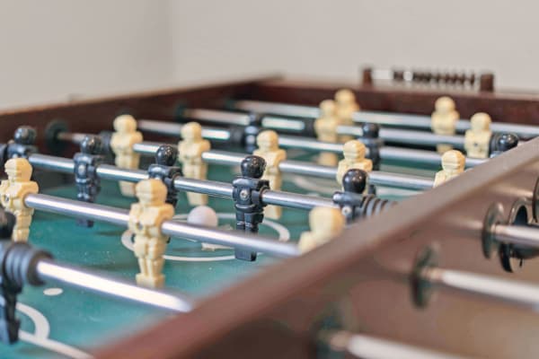 Foosball table with black and beige figurines and a white ball.