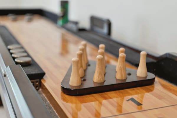 Close-up view of a shuffleboard table featuring wooden pins and metallic pucks.