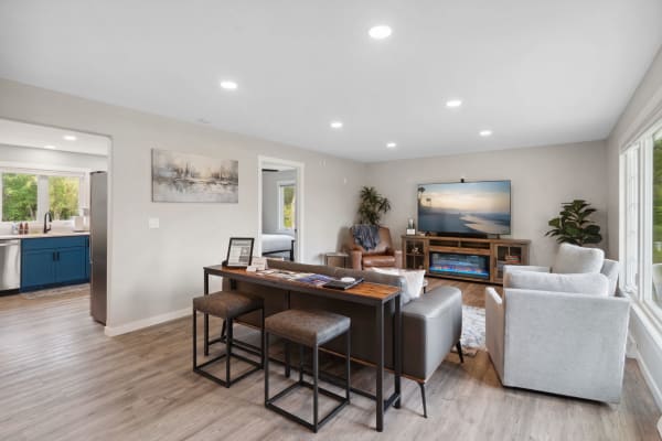 Open-concept living space featuring a modern sofa, bar table, and kitchen with blue cabinets.
