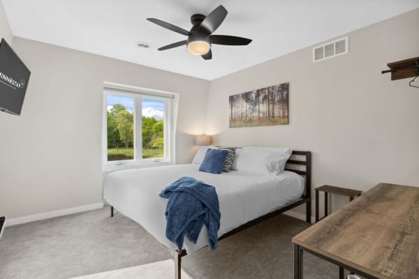 Cozy bedroom with a bed, decorative pillows, and a view of greenery outside.