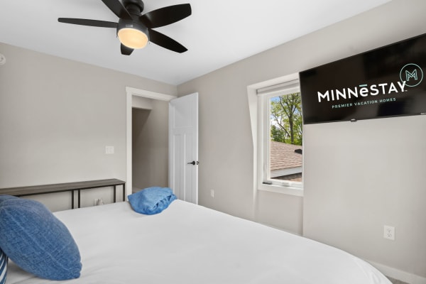 Cozy modern bedroom featuring a bed with blue pillows and a TV on the wall.