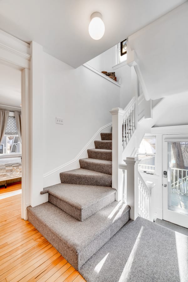 Interior staircase with grey carpeting and white walls, leading to upper floors of a home.