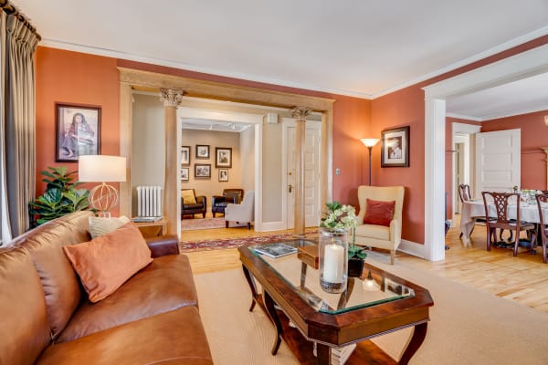 Cozy living room featuring a brown leather sofa, decorative accents, and an archway to another space.