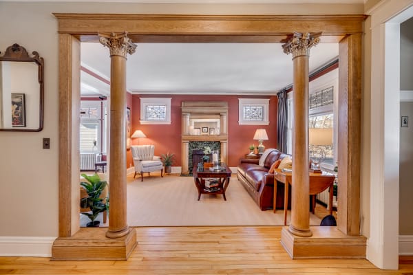 Interior view of a cozy living room with ornate columns, rich red walls, and stylish furniture.