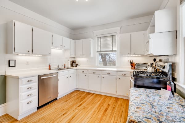 Bright kitchen featuring white cabinets, stainless steel appliances, and wooden flooring.