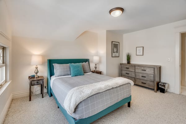 Cozy bedroom with teal bed, gray bedding, and modern lamps.