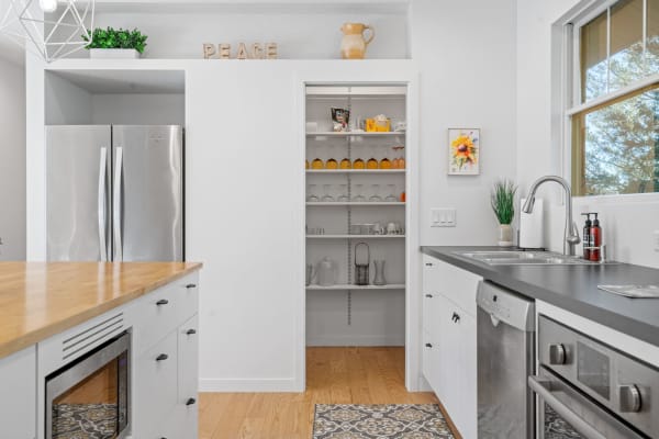 Modern kitchen with stainless steel appliances and a wooden countertop, featuring an organized pantry and decorative accents.