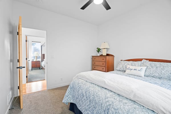 Cozy bedroom with blue patterned bedding and a lamp on a dresser.