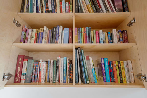 A wooden bookshelf containing various books of different sizes and colors.