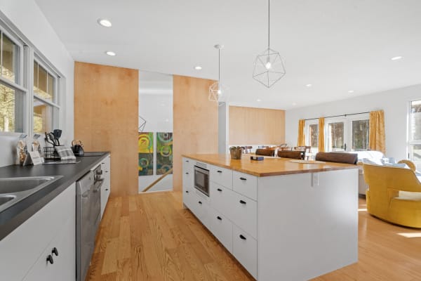 Modern kitchen with white cabinets, dark countertops, and geometric pendant lights.