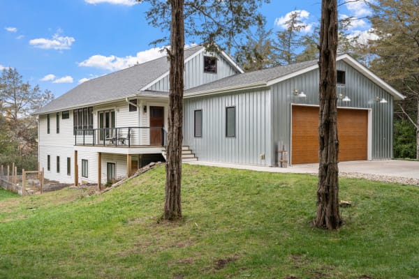 Two-story house featuring white siding and metallic cladding on a green lawn.