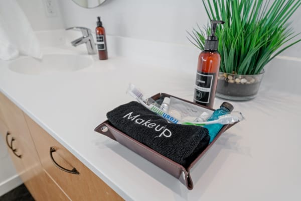 Brown tray with toiletries on a bathroom counter.