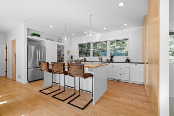 A bright and airy modern kitchen featuring a wooden island and leather bar stools.