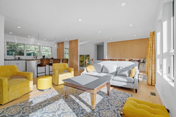 Modern living room with yellow furniture and a sleek kitchen.