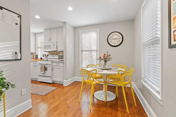 Cozy kitchen area featuring a round table with yellow chairs, a white kitchen, and hardwood floors.
