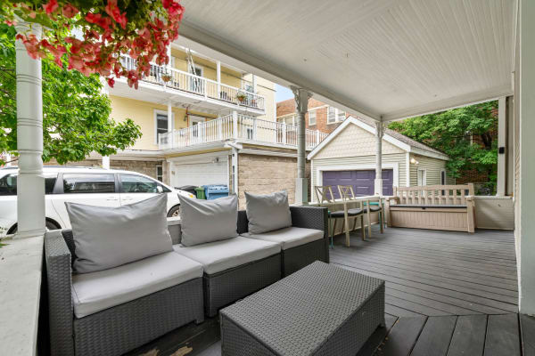 Outdoor patio area with a sectional couch, coffee table, and hanging flowers.