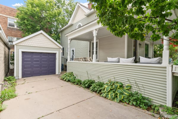 Light green house with a porch and a small purple garage in a residential neighborhood.