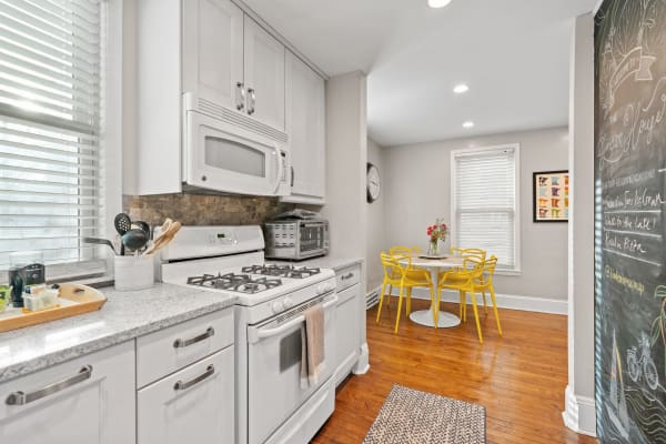 Interior view of a modern kitchen with white cabinets, yellow chairs, and a chalkboard wall.