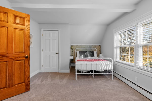 A bright bedroom with a bed, windows, and doors, showcasing a warm interior decor.