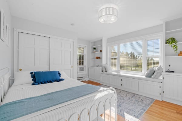 Contemporary bedroom featuring a white metal bed and a cozy window seat.