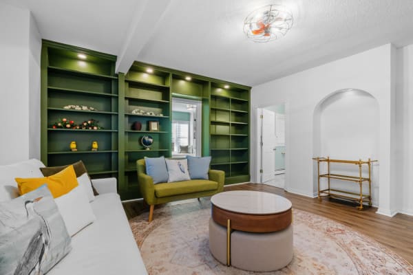 A modern living room with green shelves, a white sectional sofa, and a circular coffee table.