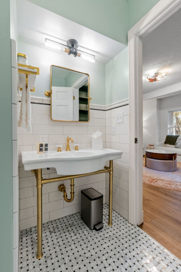 Modern bathroom with a mint green wall, gold fixtures, and a sleek white sink.