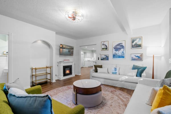 Cozy living room featuring a gray sofa, green armchair, fireplace, and bird artwork.