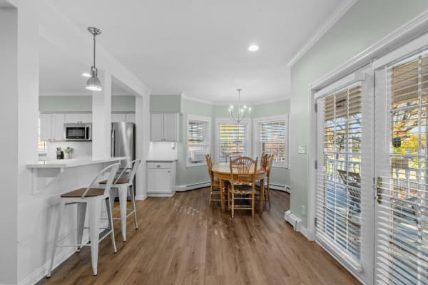 Interior view of a modern kitchen and dining area featuring a round wooden table and metal stools at the counter.