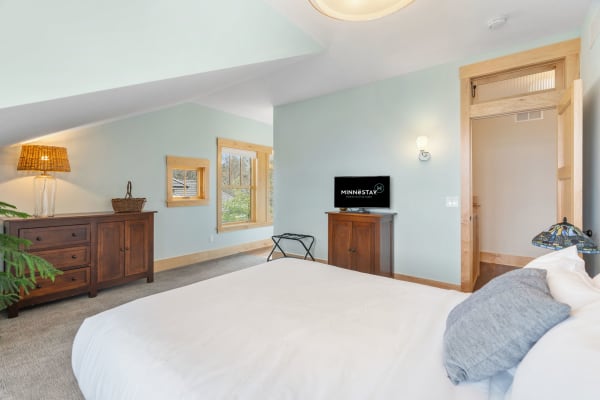 Relaxing bedroom with a king-sized bed, wooden dresser, and windows.
