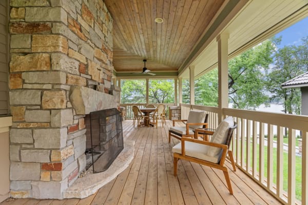 Covered porch with a stone fireplace and comfortable seating.