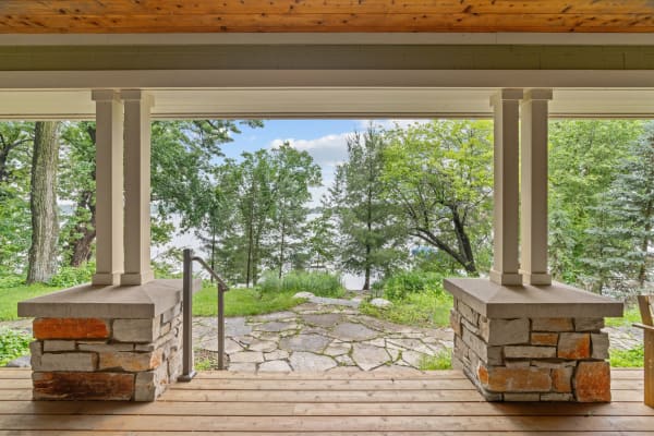 View from a porch overlooking green trees and a lake.