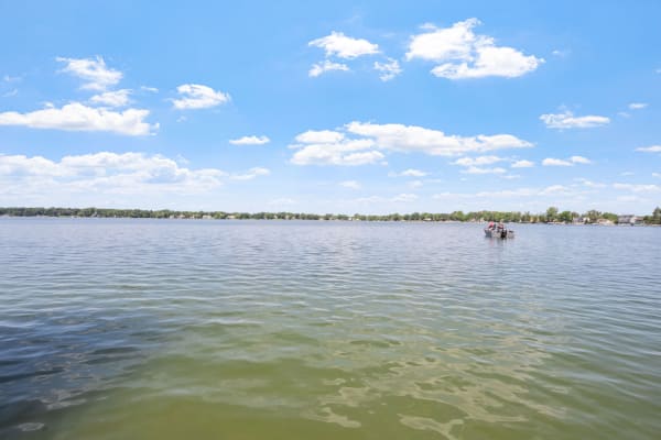 A calm lake with rippling water, a small boat, and a vibrant blue sky.