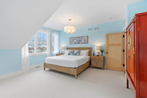 Bright bedroom with a wooden bed, decorative pillows, and a red cabinet.