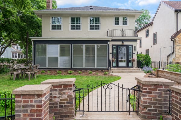 Two-story house with a porch and garden path, surrounded by trees.