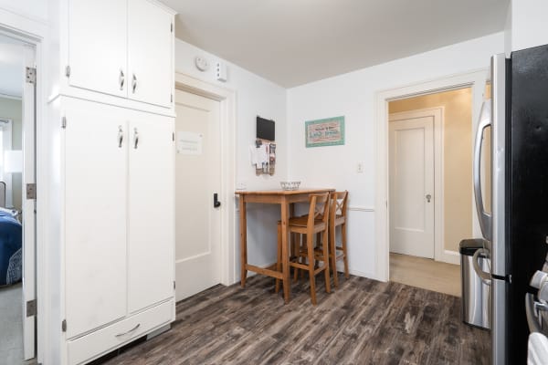 Interior view of a welcoming kitchen with a small wooden table and white cabinets.