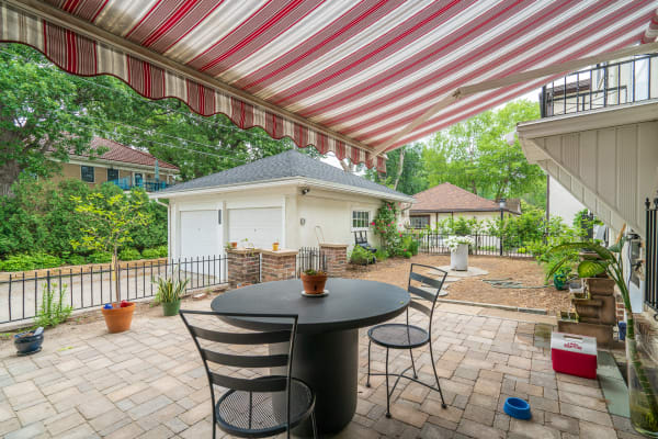 Outdoor patio area with round table, chairs, and colorful awning.