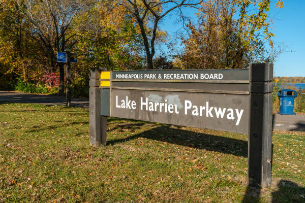 Sign for Lake Harriet Parkway with colorful autumn trees in the background.