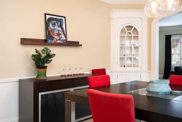 Contemporary dining room with red chairs, a dark wooden table, abstract artwork, and a decorative sideboard.