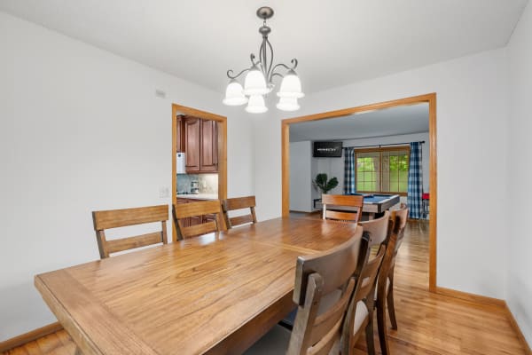 Interior view of a dining area with wooden table and chandelier, leading to other rooms.