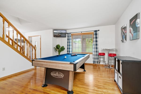 Interior view of a game room with billiard table, bar stools, and window.
