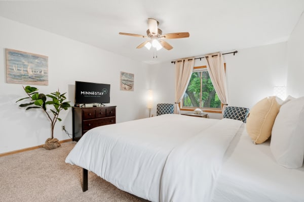 Cozy bedroom with a queen-sized bed, wooden furniture, and decorative wall art.