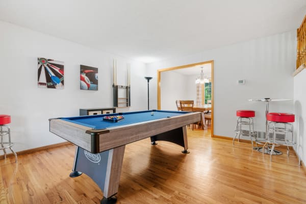 Game room featuring a blue pool table, artworks on the wall, and a dining area in the background.