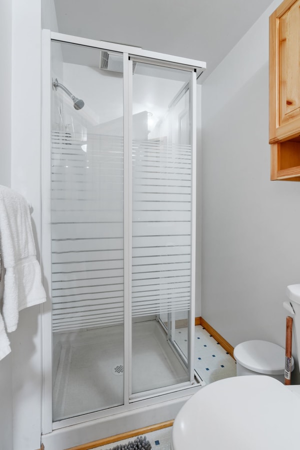 A clean bathroom with a glass shower, towel, and decorative elements.