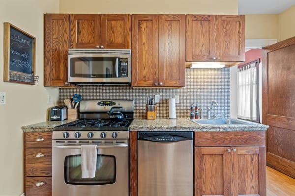 A modern kitchen featuring wooden cabinets, stainless steel appliances, and a granite countertop.
