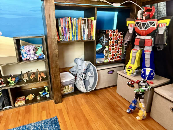 An organized playroom with a large colorful robot, action figures, plush toys, and books.