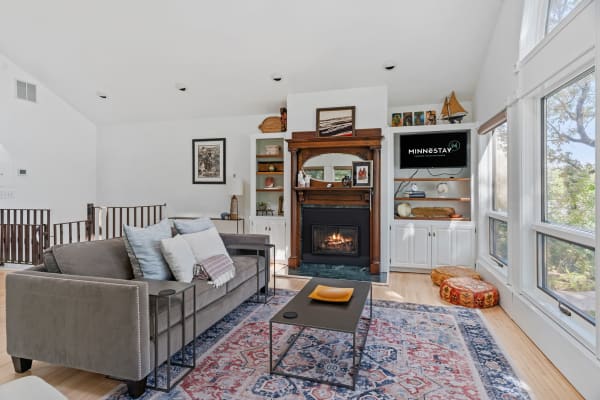 Living room with gray sofa, fireplace, and large windows.