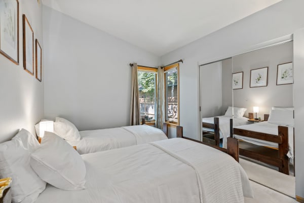 Twin beds in a cozy, well-lit bedroom with botanical artwork on the walls.
