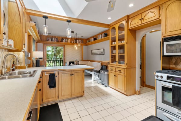 Warm wooden kitchen with a modern sink and dining nook, illuminated by pendant lights.