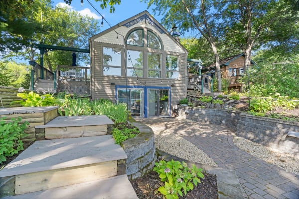 A unique home with large windows and a landscaped garden featuring wooden steps and stone pathways.